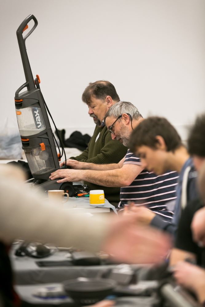 Repairers fixing a vacuum cleaner.