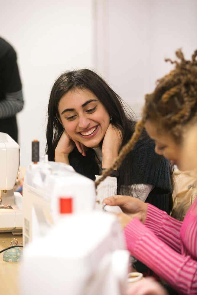 Girls sitting at a sewing machine during a workshop.